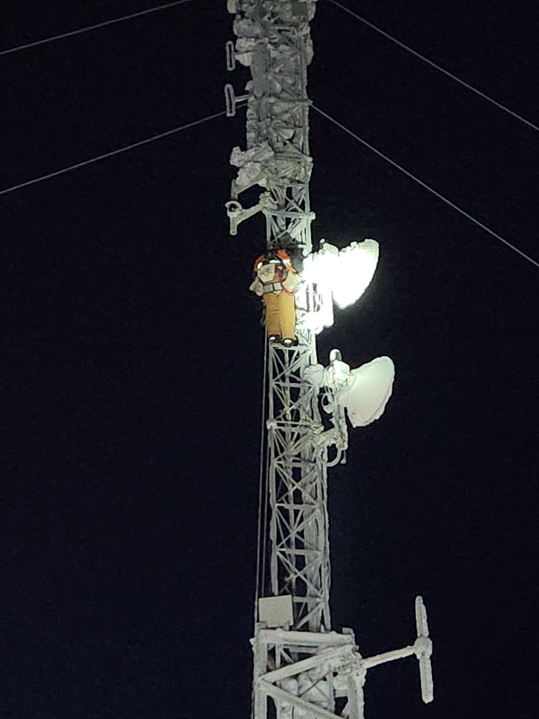 Climber working at night on iced tower with headlamp
